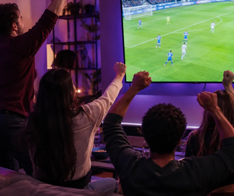 Amis célébrant devant un match diffusé en direct sur une grande TV
